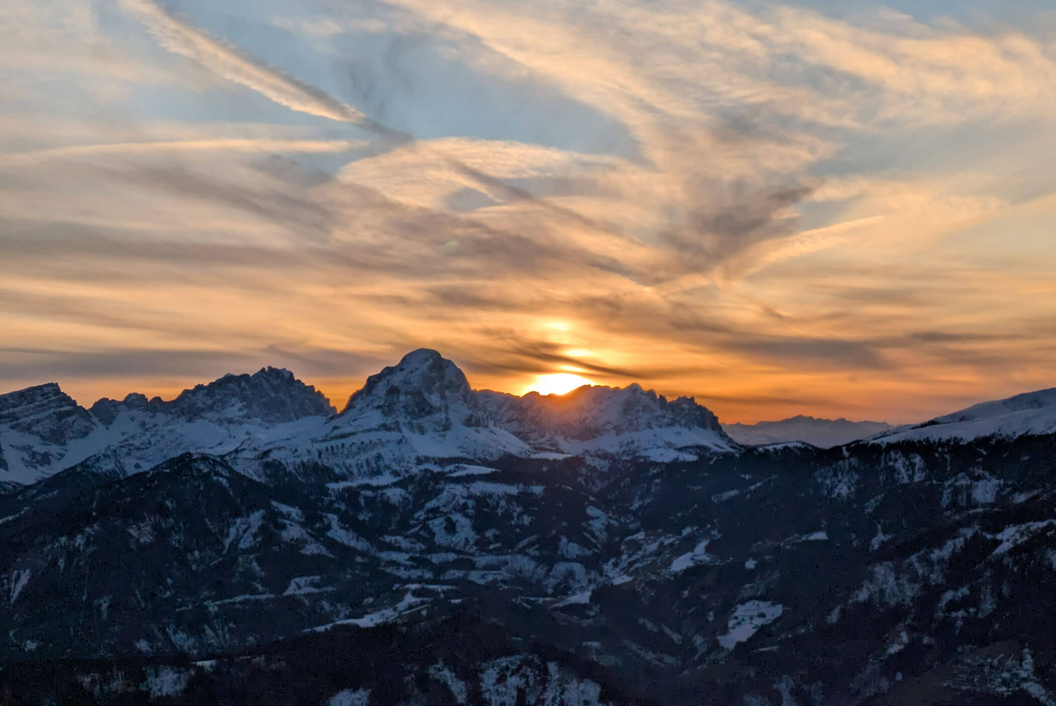 Sonnenuntergang über schneebedeckten Bergen mit dramatischen, streifigen Wolken am Himmel. - Residence Aichner